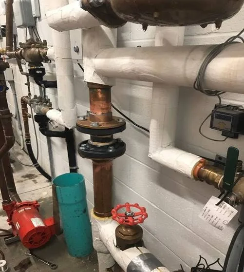 Close-up of a Water Flow Management device installed in a building mechanical room